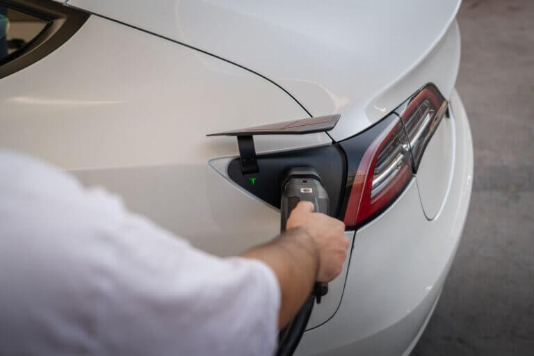 A white Tesla Model 3 plugged in at a charging point