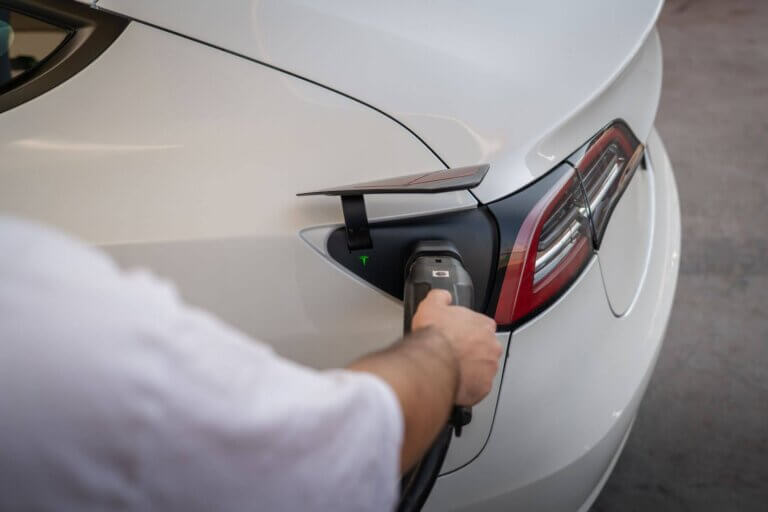 Een witte Tesla Model 3 aan het opladen bij een laadpunt